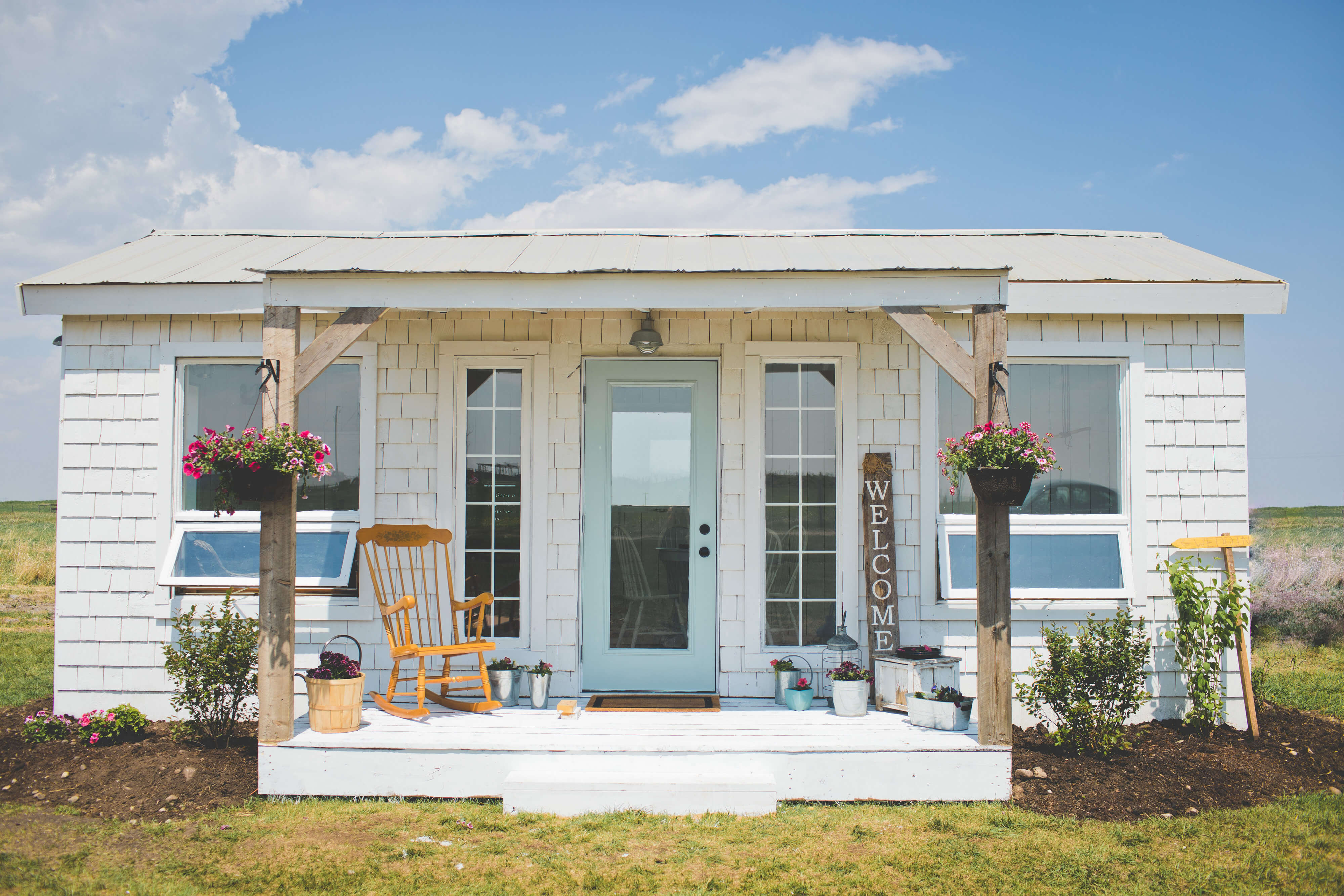 garden cottage a white cottage with a baby blue door, little front porch with a rocking chair sitting on it