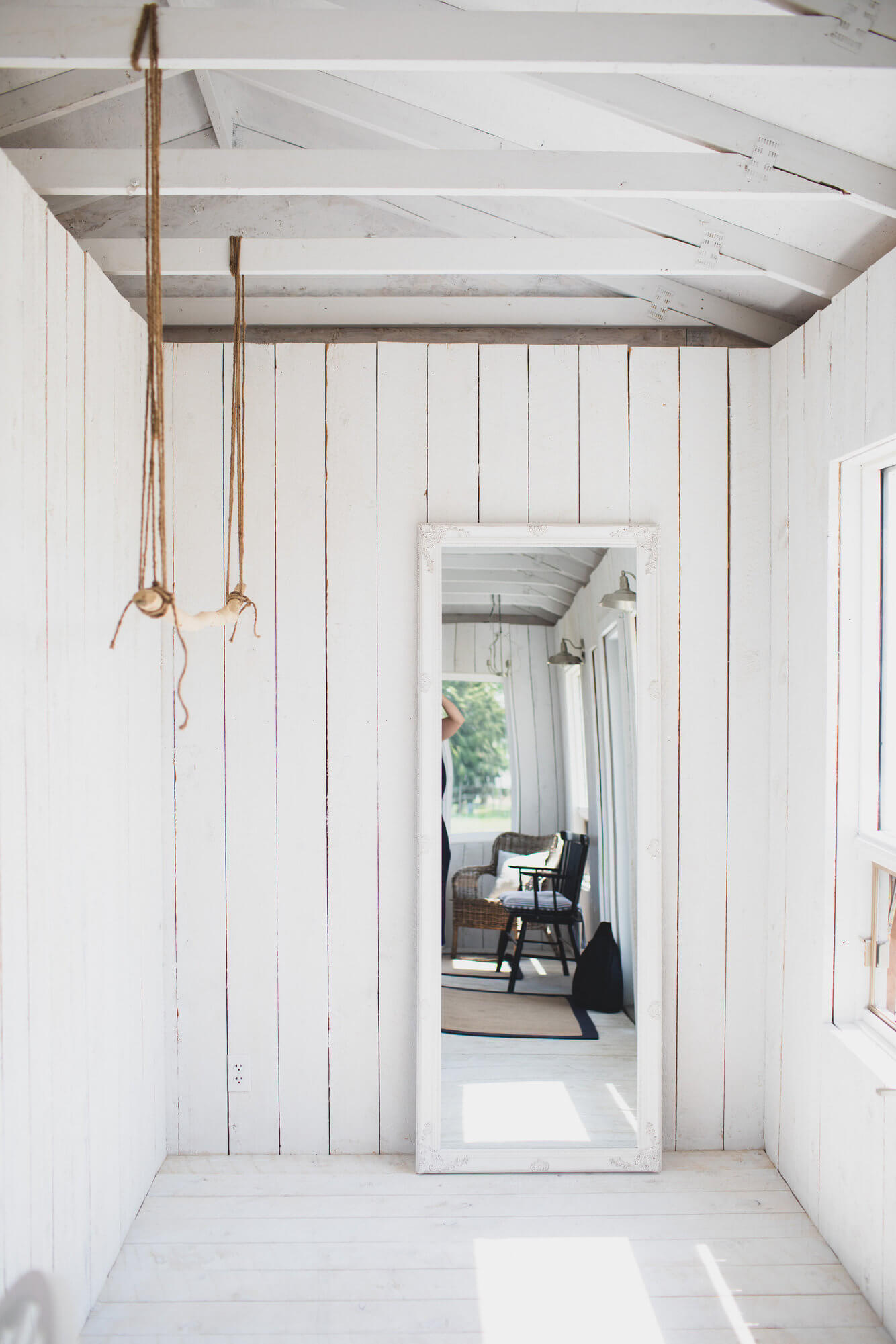 garden cottage white shiplap wood wall, open beam white room with a large white mirror and a branch hanging down